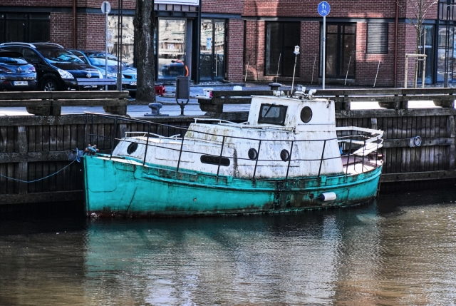 A picturesque boat parked along the river down town.  I hope no one goes out into the open sea in it.